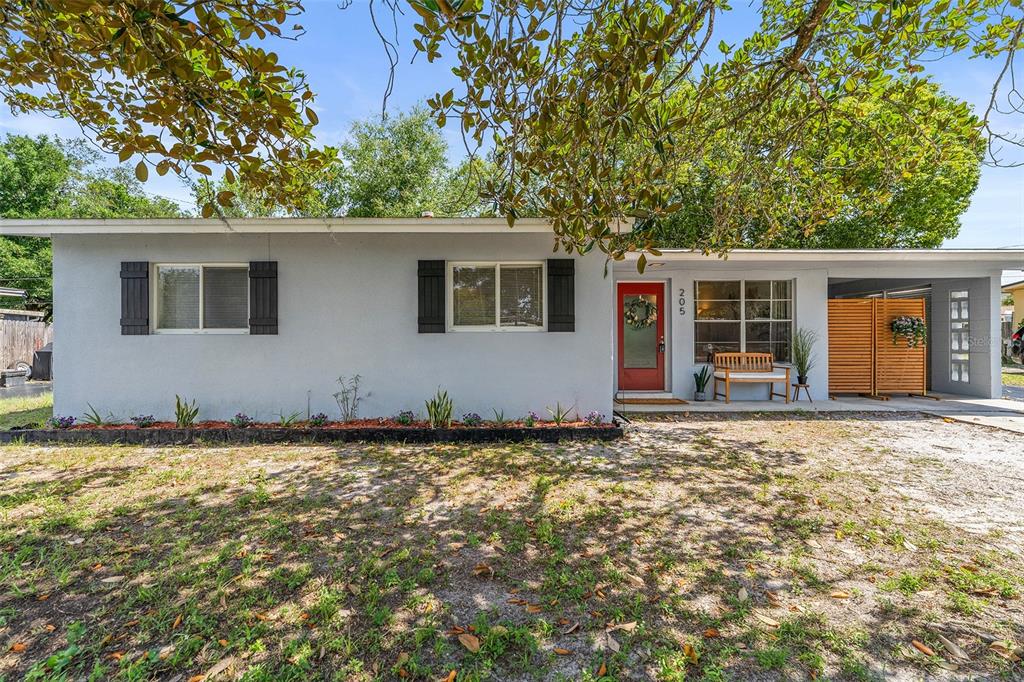 A single-story house with a gray exterior, red front door, and a covered carport — 205 WILSHIRE DRIVE, CASSELBERRY, FL