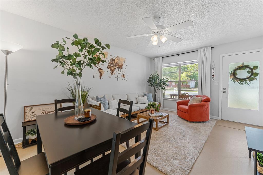 A living and dining area features a white sofa, orange armchair, and dark wood table — 205 WILSHIRE DRIVE, CASSELBERRY, FL