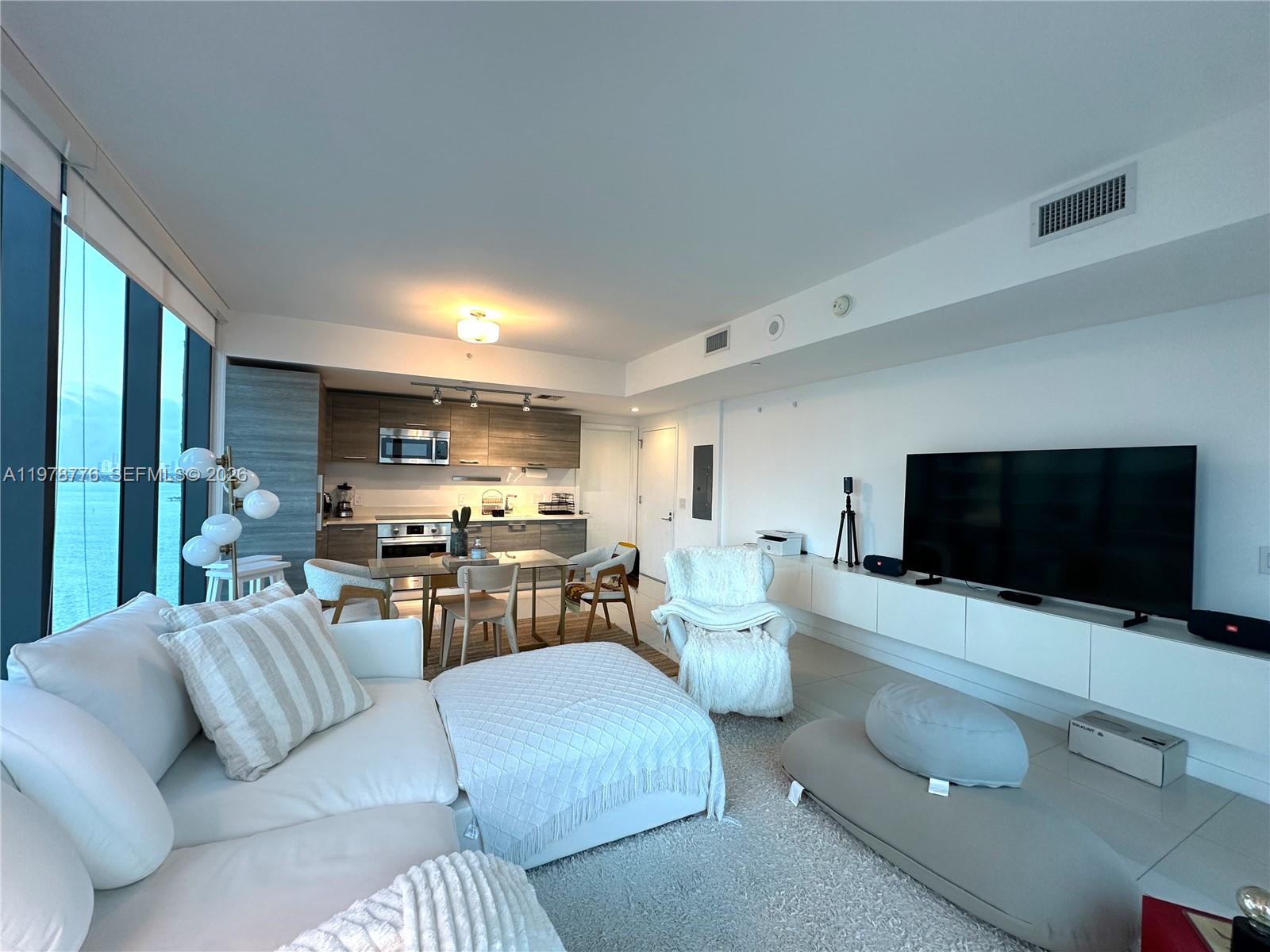 A modern living room and kitchen area with white furniture, tile floors, and floor-to-ceiling windows — 650 NE 32nd St # 2108, Miami FL 33137, MIAMI, FL