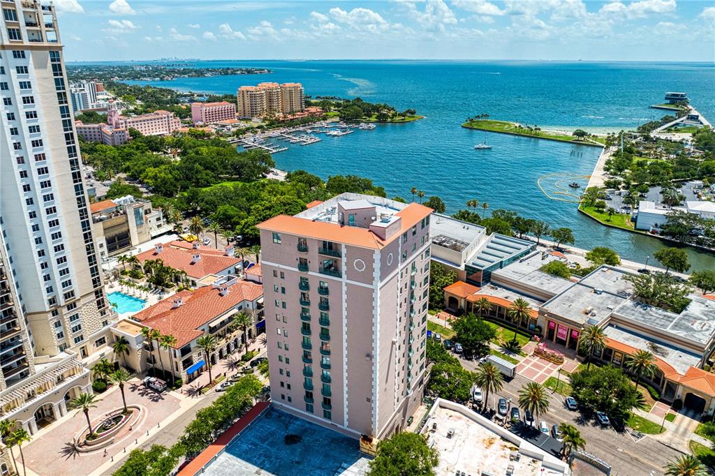 An aerial view shows a tall tan apartment building overlooking a bay and marina — 288 BEACH DRIVE NE UNIT PH-2A, ST PETERSBURG, FL