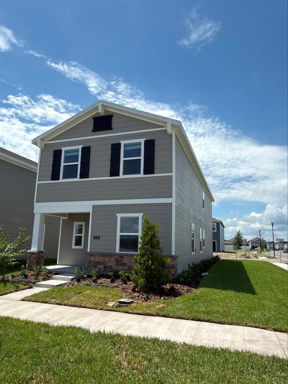 A two-story house with gray horizontal siding, black shutters, and a stone-accented front porch — 5161 MARLBERRY COURT, ST CLOUD, FL