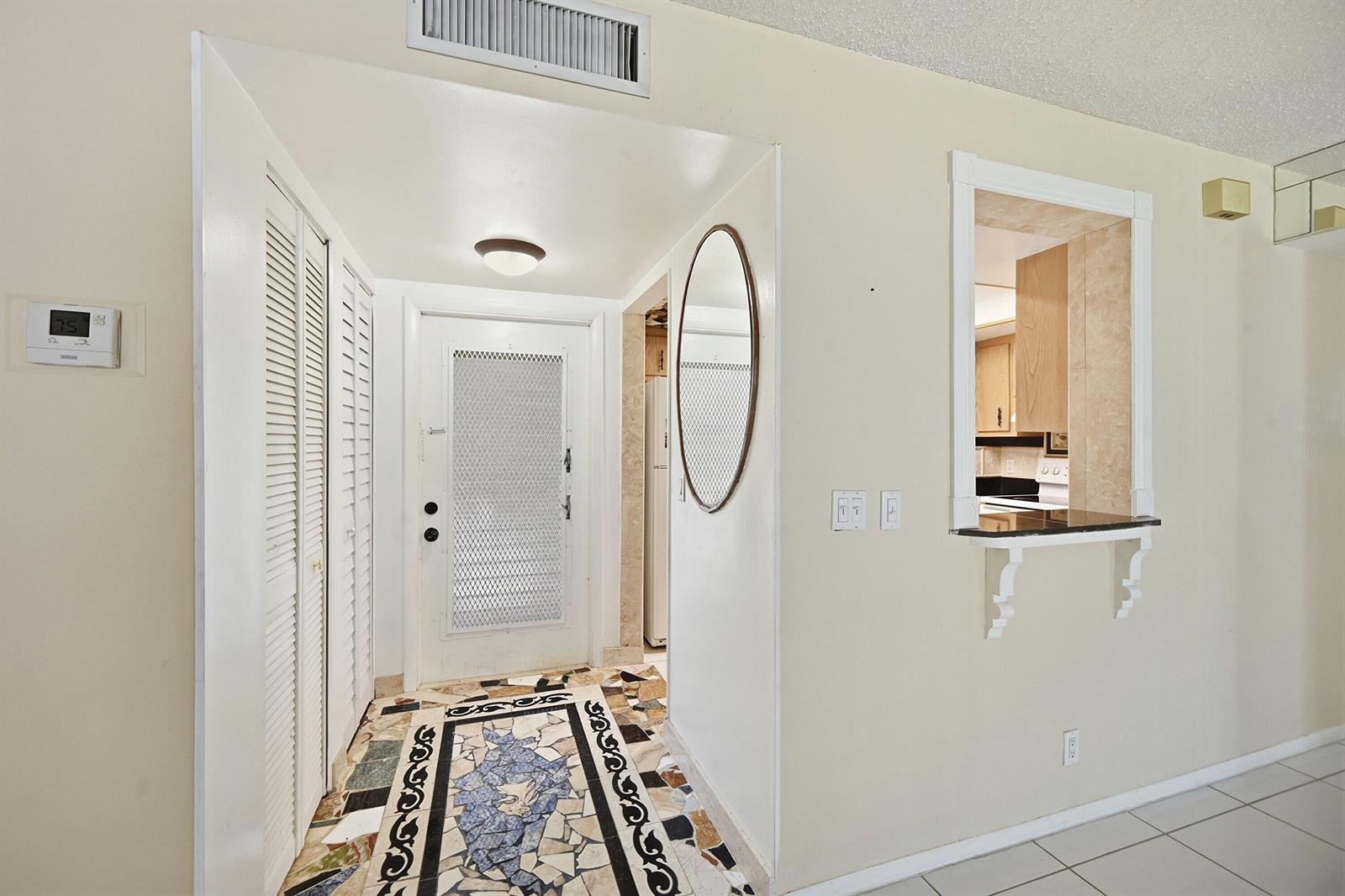 An entryway features a mosaic tile floor, a white door, and a kitchen pass-through window — 6525 S Oriole Boulevard, Delray Beach FL 33446, DELRAY BEACH, FL