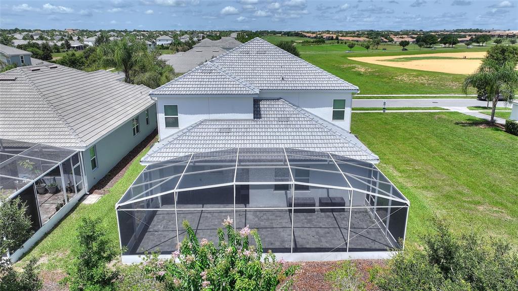 An aerial view shows a two-story house with a screened-in patio and tile roof — 1380 OLYMPIC CLUB BOULEVARD, CHAMPIONS GATE, FL