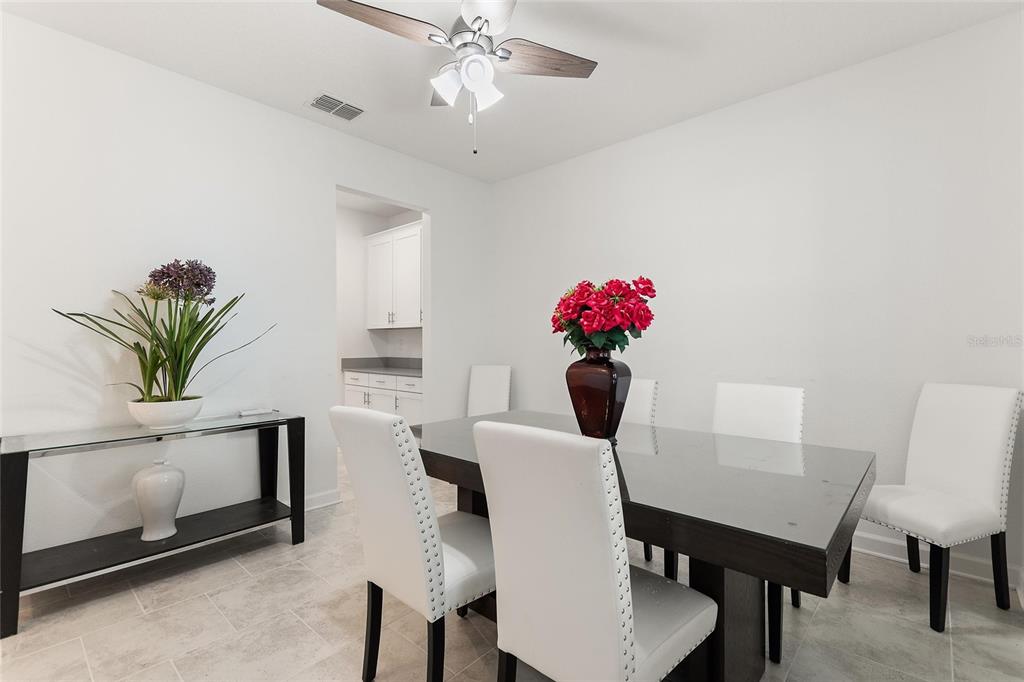 A dining room features a dark table, white chairs, a ceiling fan, and tile flooring — 1380 OLYMPIC CLUB BOULEVARD, CHAMPIONS GATE, FL