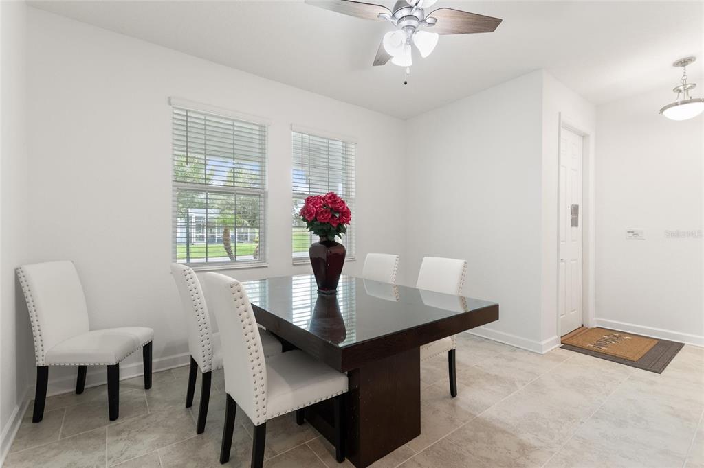 A dining room features a dark table, white upholstered chairs, tile flooring, and a ceiling fan — 1380 OLYMPIC CLUB BOULEVARD, CHAMPIONS GATE, FL