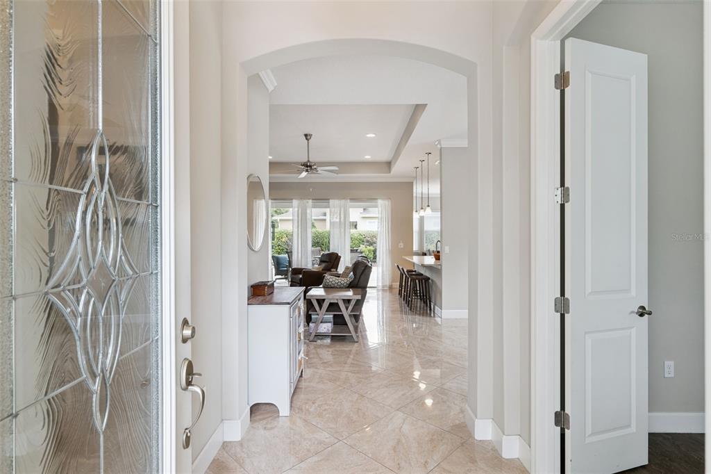 A view from an entryway looking through an arched doorway into an open-concept living area — 1365 BRAYFORD POINT, DELAND, FL
