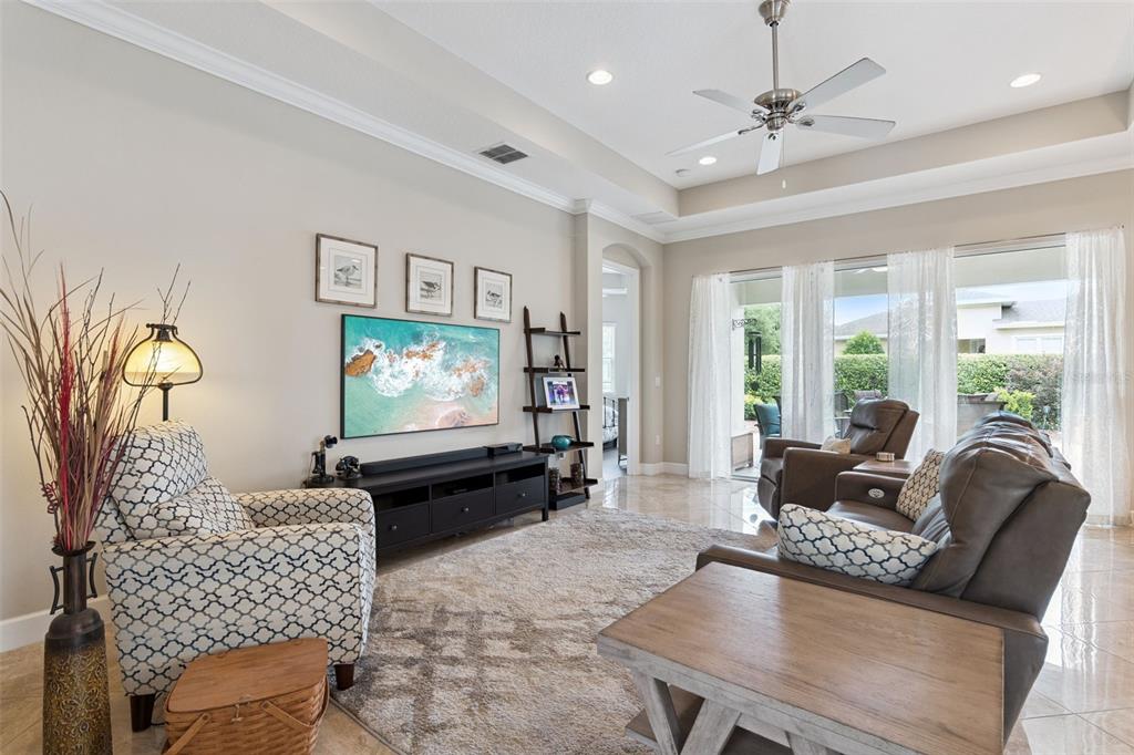 A living room features a television, patterned armchairs, a leather sofa, and large sliding doors — 1365 BRAYFORD POINT, DELAND, FL
