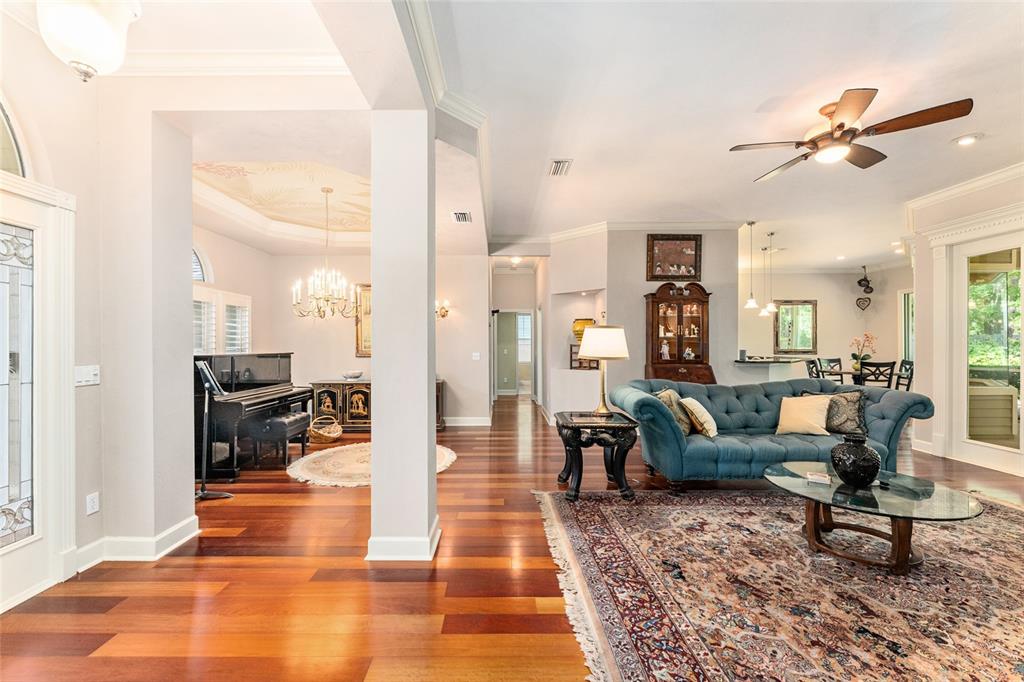An open-concept living area features hardwood floors, a blue tufted sofa, and a grand piano — 6415 SW 88TH TERRACE, GAINESVILLE, FL