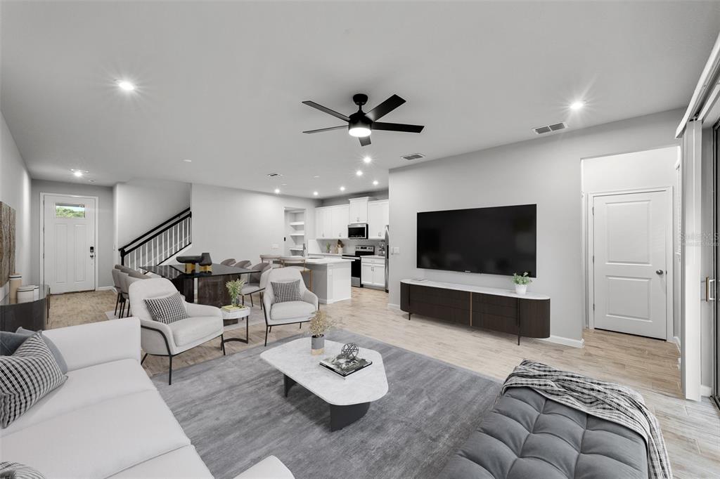 An open-concept living room and kitchen featuring light wood flooring and modern furniture — 4366 CLOUD HOPPER WAY, LUTZ, FL