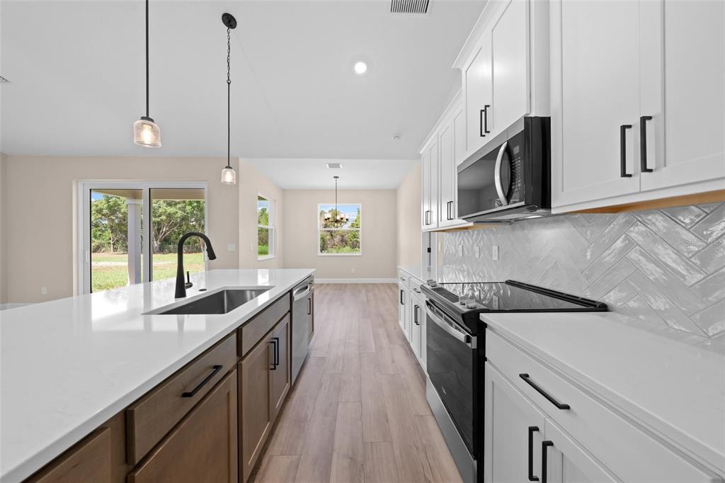 A kitchen features a large island, white upper cabinets, wood lower cabinets, and stainless appliances — 0 CORD AVENUE, ST CLOUD, FL