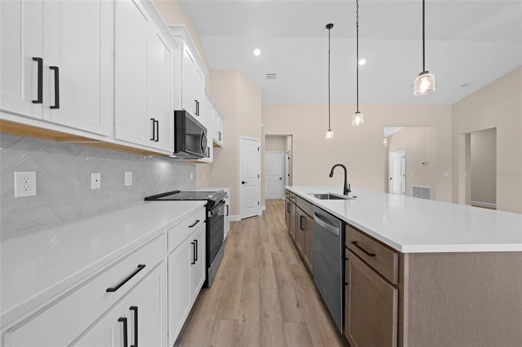 A kitchen features white upper cabinets, a brown island, and light wood-look flooring — 0 CORD AVENUE, ST CLOUD, FL