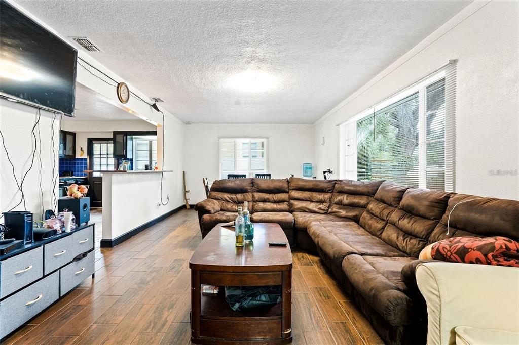A living room features a large brown sectional sofa, a wooden coffee table, and wood-look flooring — 912 DRUID ROAD E, CLEARWATER, FL