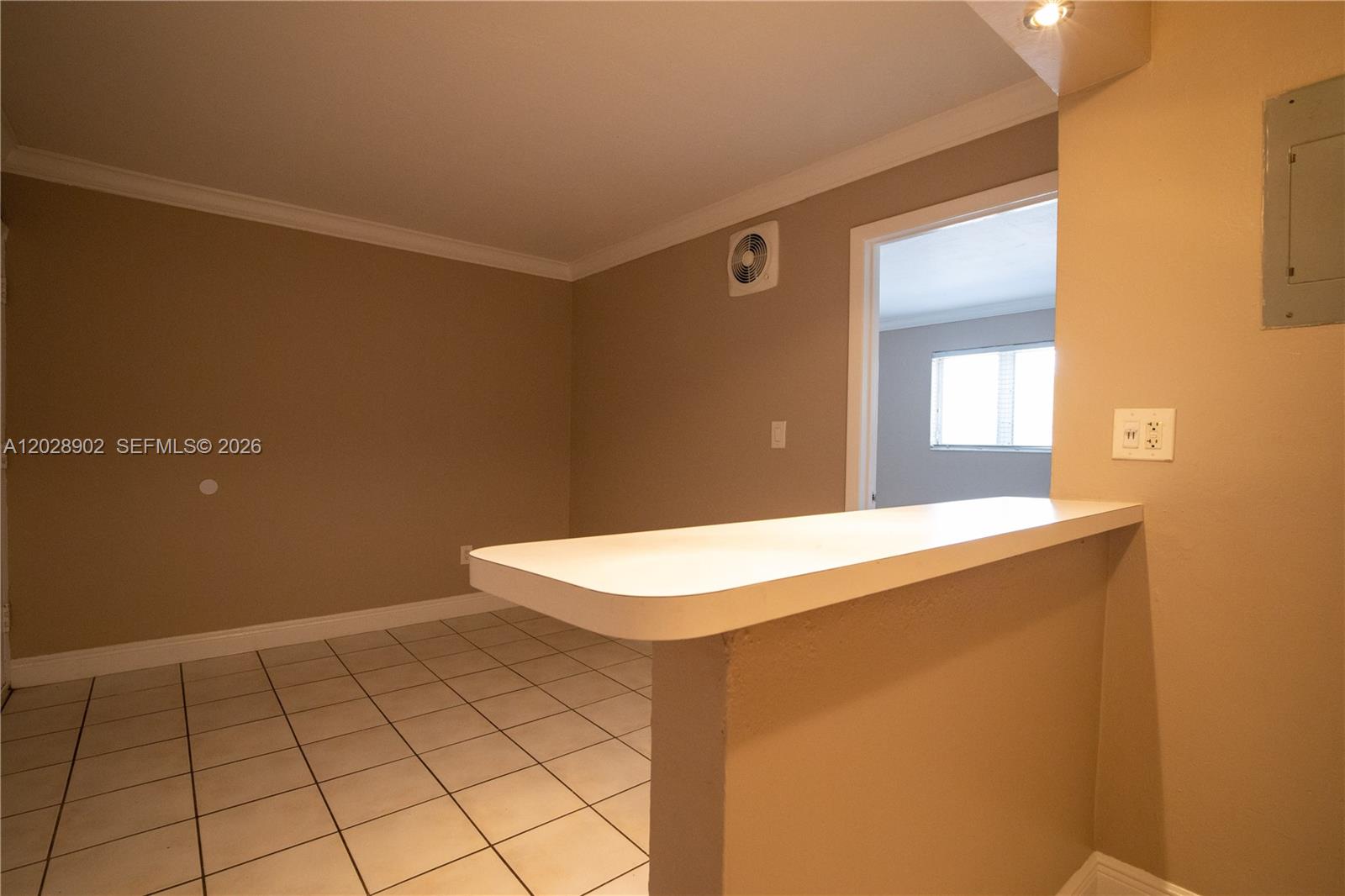 A kitchen breakfast bar overlooks a tiled dining area with a doorway to another room — 1014 Salzedo St # 101, Coral Gables FL 33134, CORAL GABLES, FL