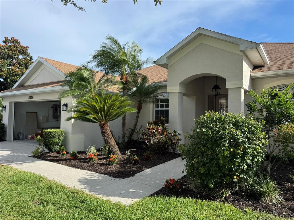 A single-story house with a beige stucco exterior, a two-car garage, and a landscaped yard — 13335 PURPLE FINCH CIRCLE, BRADENTON, FL