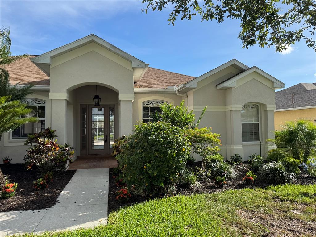 The front exterior of a single-story house features a covered entryway and landscaped garden — 13335 PURPLE FINCH CIRCLE, BRADENTON, FL