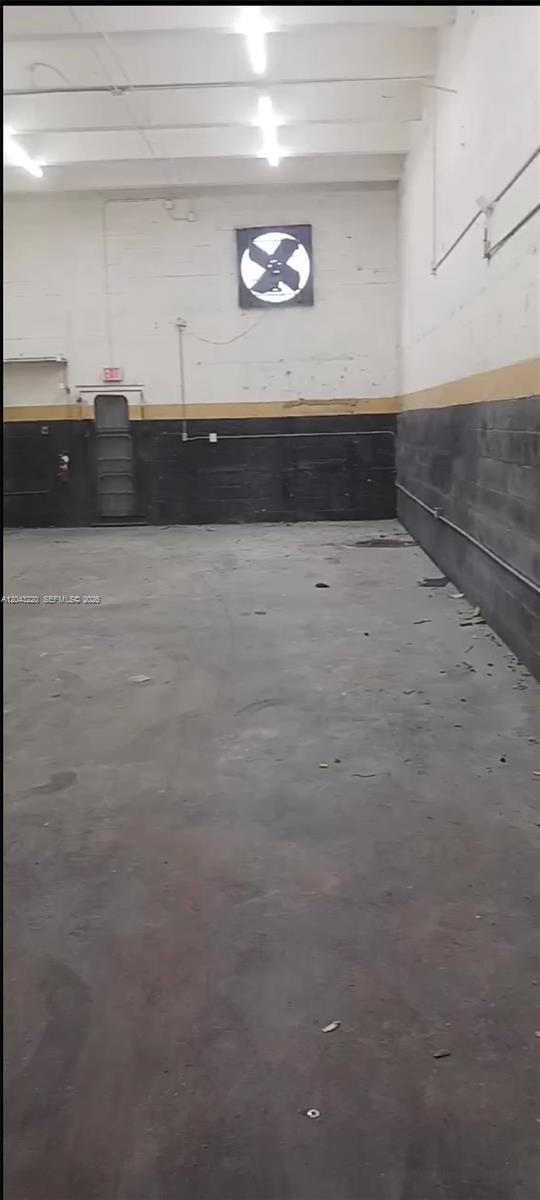 An empty industrial warehouse space features concrete floors, block walls, and an exhaust fan — 14246 SW 139th Ct, Miami FL 33186, MIAMI, FL
