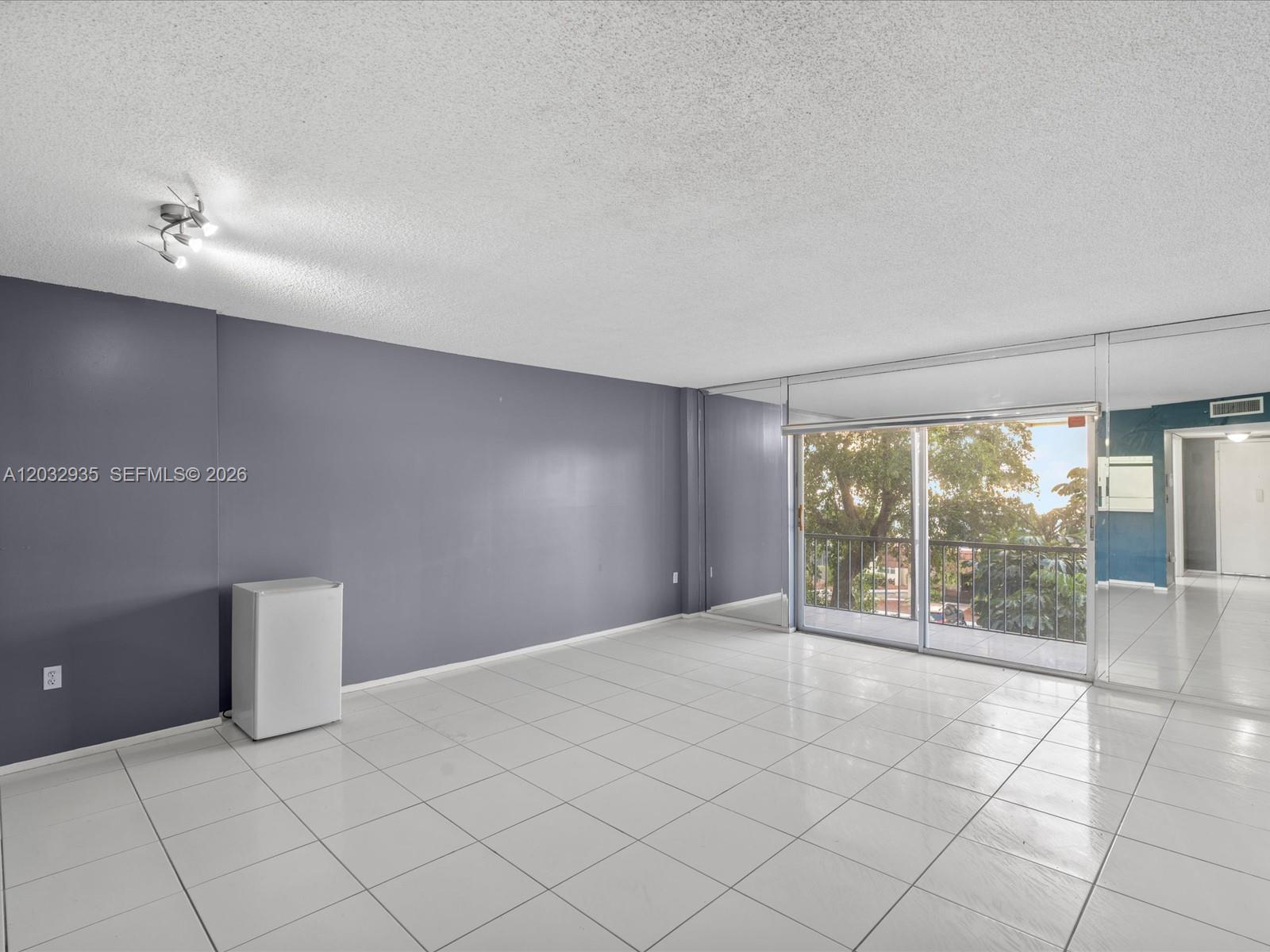 A room with white tile floors, a gray accent wall, and a sliding glass door — 4172 Inverrary Dr # 306, Lauderhill FL 33319, LAUDERHILL, FL