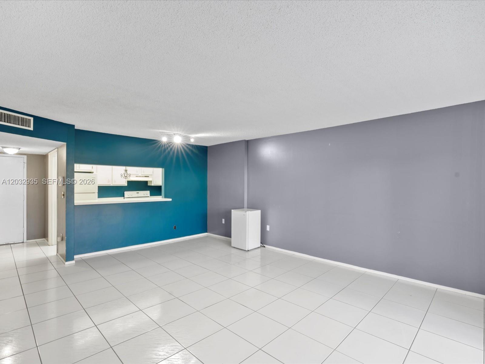 An empty room features white tile floors, a teal accent wall, and a gray wall — 4172 Inverrary Dr # 306, Lauderhill FL 33319, LAUDERHILL, FL
