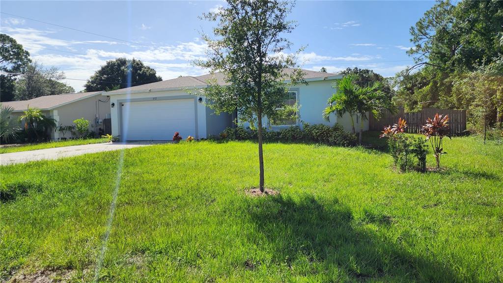 A single-story house with a white garage and a green lawn under a blue sky — 832 SORREL STREET NW, PALM BAY, FL