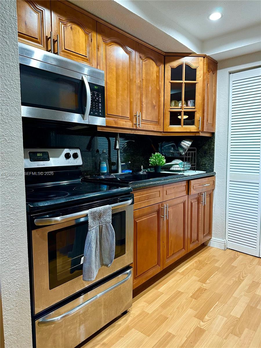 A kitchen features wood cabinets, stainless steel appliances, and a dark countertop — 500 NE 2nd St # 327, Dania Beach FL 33004, DANIA BEACH, FL