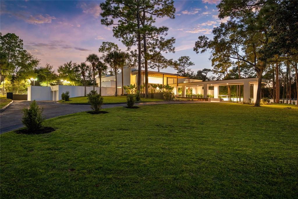 A modern white house with a long driveway and palm trees sits on a grassy lot — 808 SWEETWATER CLUB BOULEVARD, LONGWOOD, FL