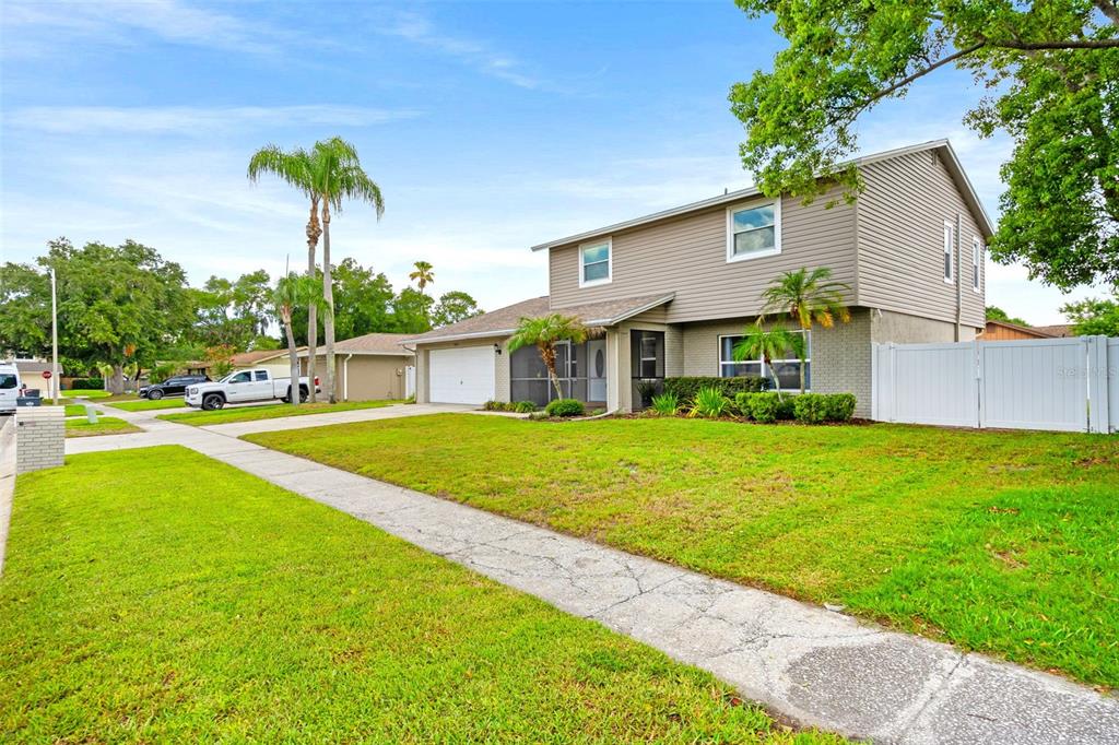 A two-story house with tan siding, a white garage, and a front lawn — 4029 BELL GRANDE DRIVE, VALRICO, FL