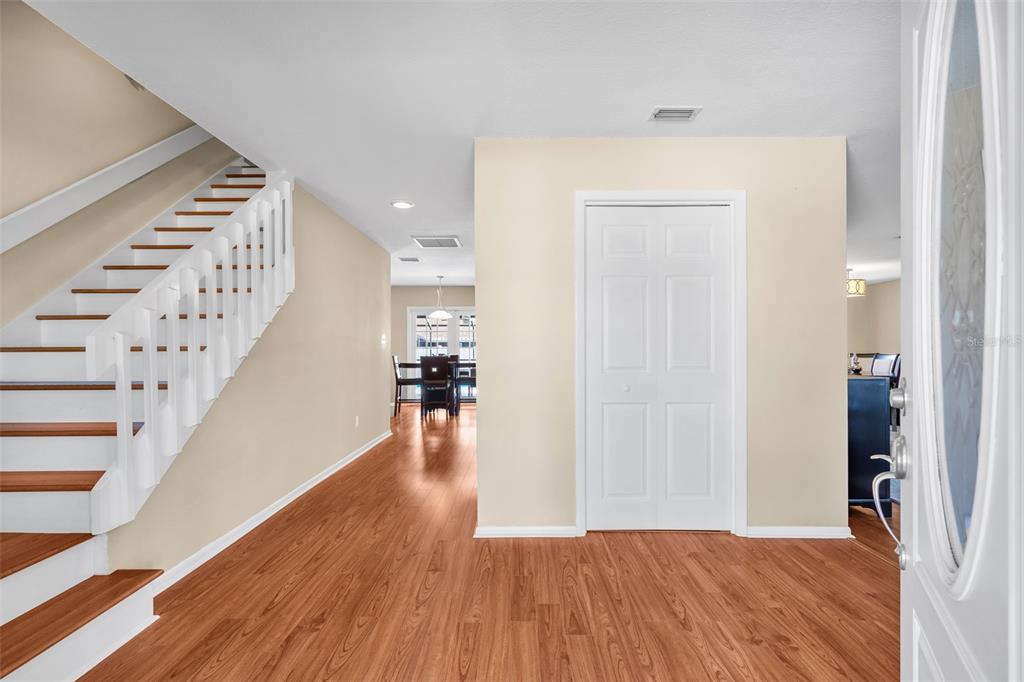 An entryway with wood-look flooring, a staircase with white railings, and a closed white door — 4029 BELL GRANDE DRIVE, VALRICO, FL