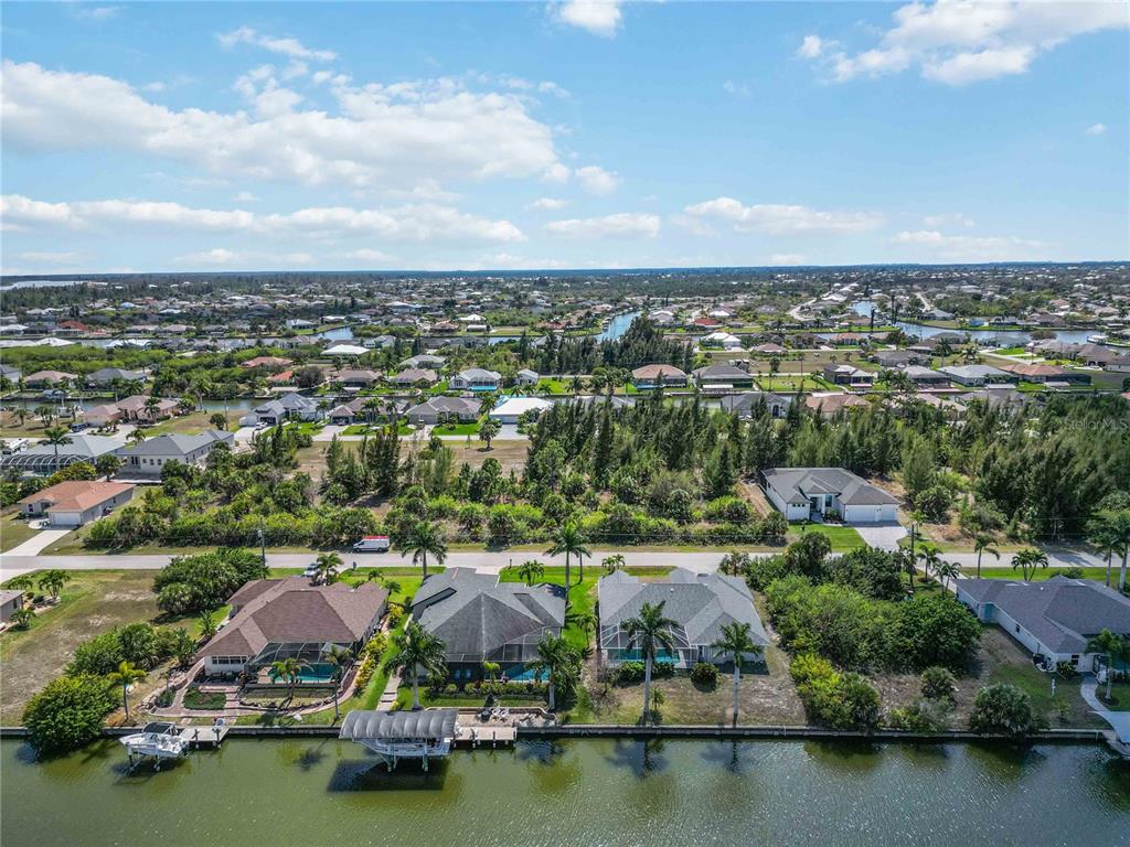An aerial view shows waterfront houses with pools and boat docks along a canal — 15609 MELPORT CIRCLE, PORT CHARLOTTE, FL