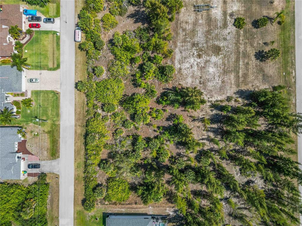An aerial view shows a vacant, wooded residential lot situated between two paved streets — 15609 MELPORT CIRCLE, PORT CHARLOTTE, FL