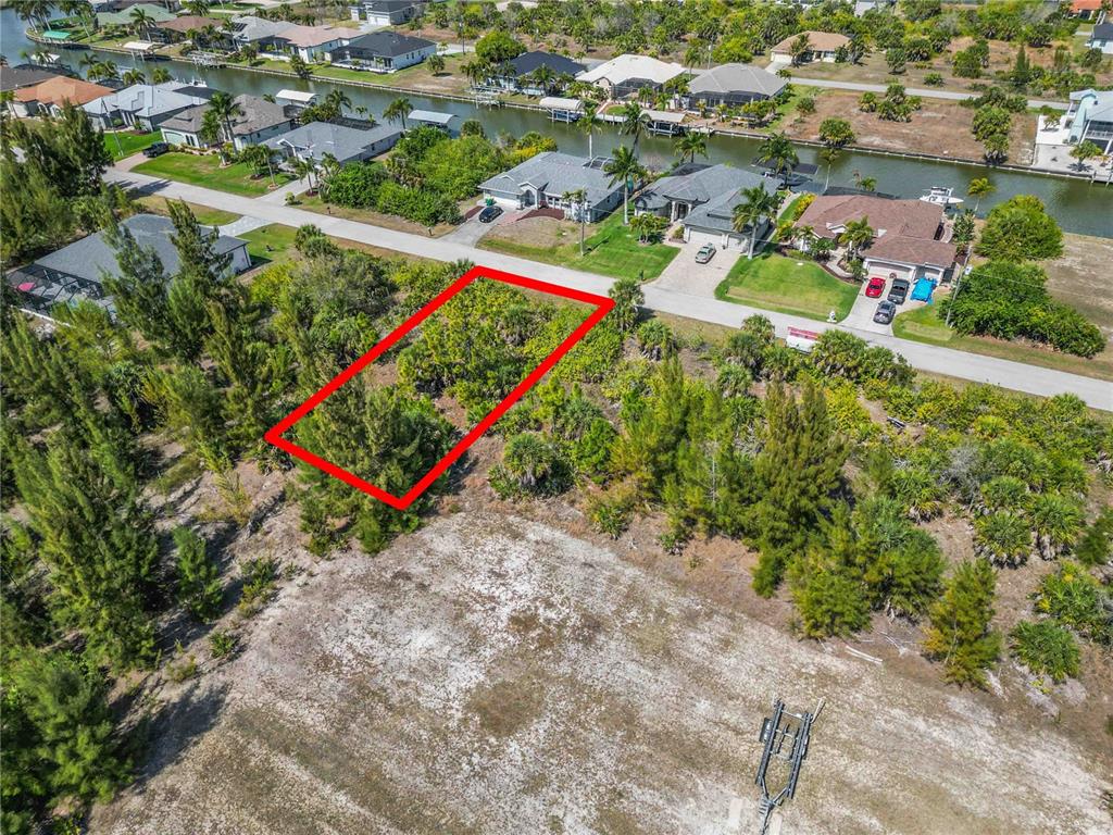 An aerial view shows a vacant, rectangular residential lot outlined in red near a canal — 15609 MELPORT CIRCLE, PORT CHARLOTTE, FL