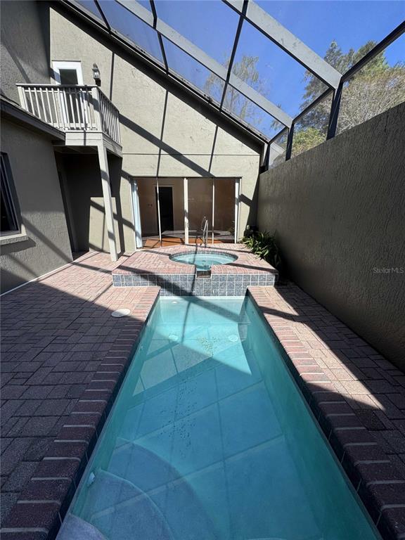 A narrow rectangular swimming pool and an elevated spa are enclosed within a screened patio — 1701 SE 28TH STREET, OCALA, FL