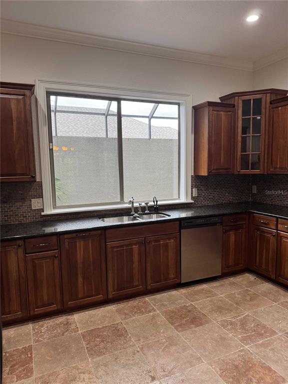 A kitchen features wood cabinets, dark granite countertops, a stainless dishwasher, and stone tile flooring — 1701 SE 28TH STREET, OCALA, FL