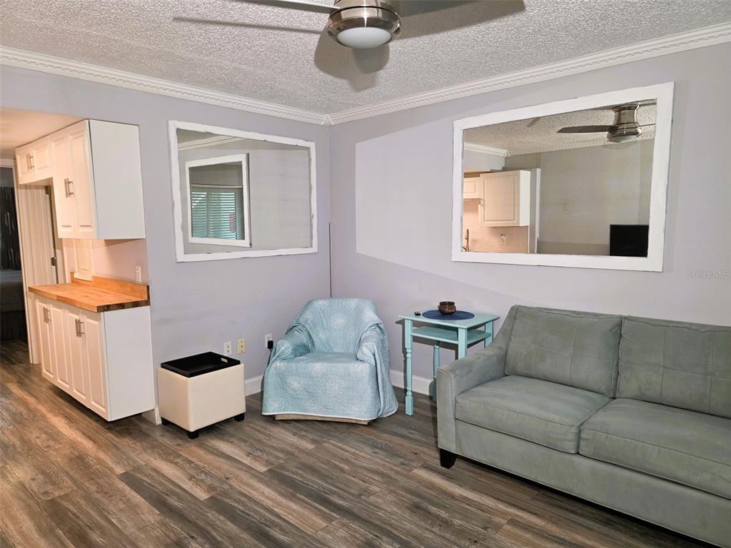 A living room with wood-look flooring, a sectional sofa, and a ceiling fan — 1865 MAZO MANOR UNIT J3, LUTZ, FL