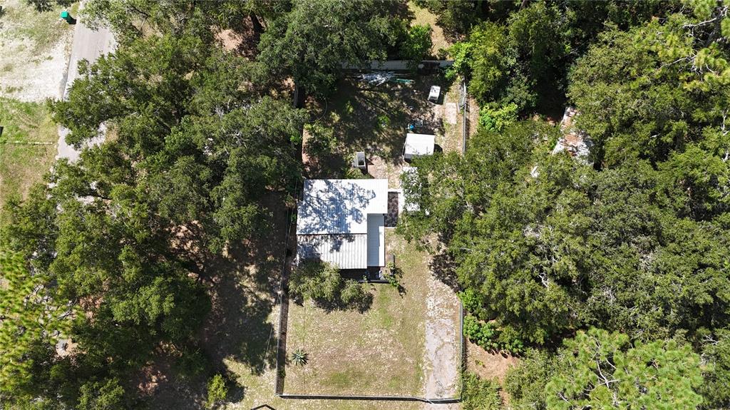 An aerial view shows a house with a metal roof surrounded by trees and fencing — 3750 HILLTOP, DUNNELLON, FL