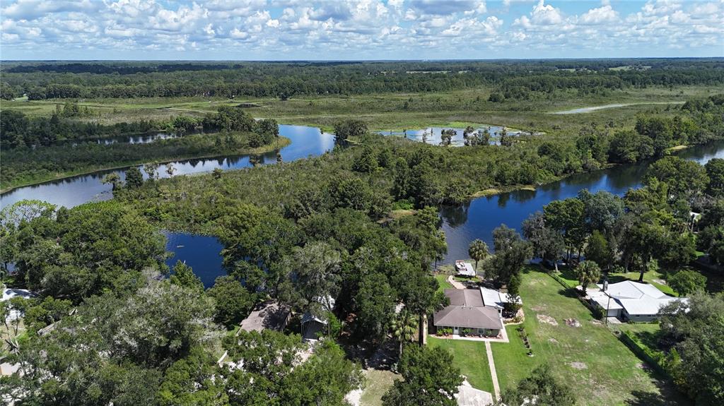 An aerial view shows a house with a yard situated along a winding river — 3750 HILLTOP, DUNNELLON, FL