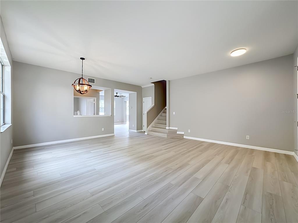 An empty living room features light wood-look flooring, gray walls, and a staircase — 1620 ATLANTIC DRIVE, RUSKIN, FL