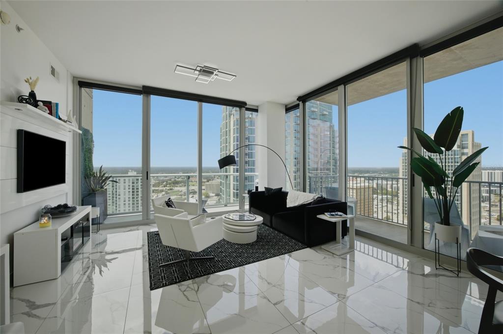 A modern living room features white marble floors, floor-to-ceiling windows, and a city skyline view — 777 N ASHLEY DRIVE UNIT 2613, TAMPA, FL