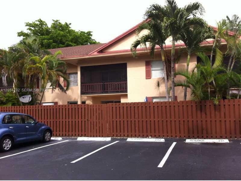 A two-story apartment building with a brown wooden fence and a parking lot in front — 11261 SW 88 ST # 205H, Miami FL 33176, MIAMI, FL