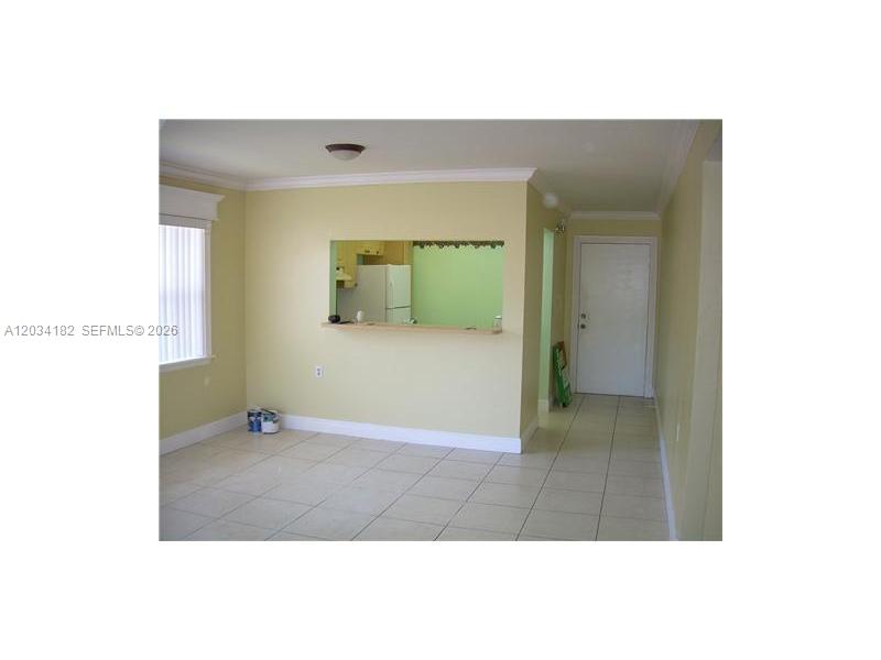 A room with light-colored tile flooring, pale yellow walls, and a kitchen pass-through window — 11261 SW 88 ST # 205H, Miami FL 33176, MIAMI, FL
