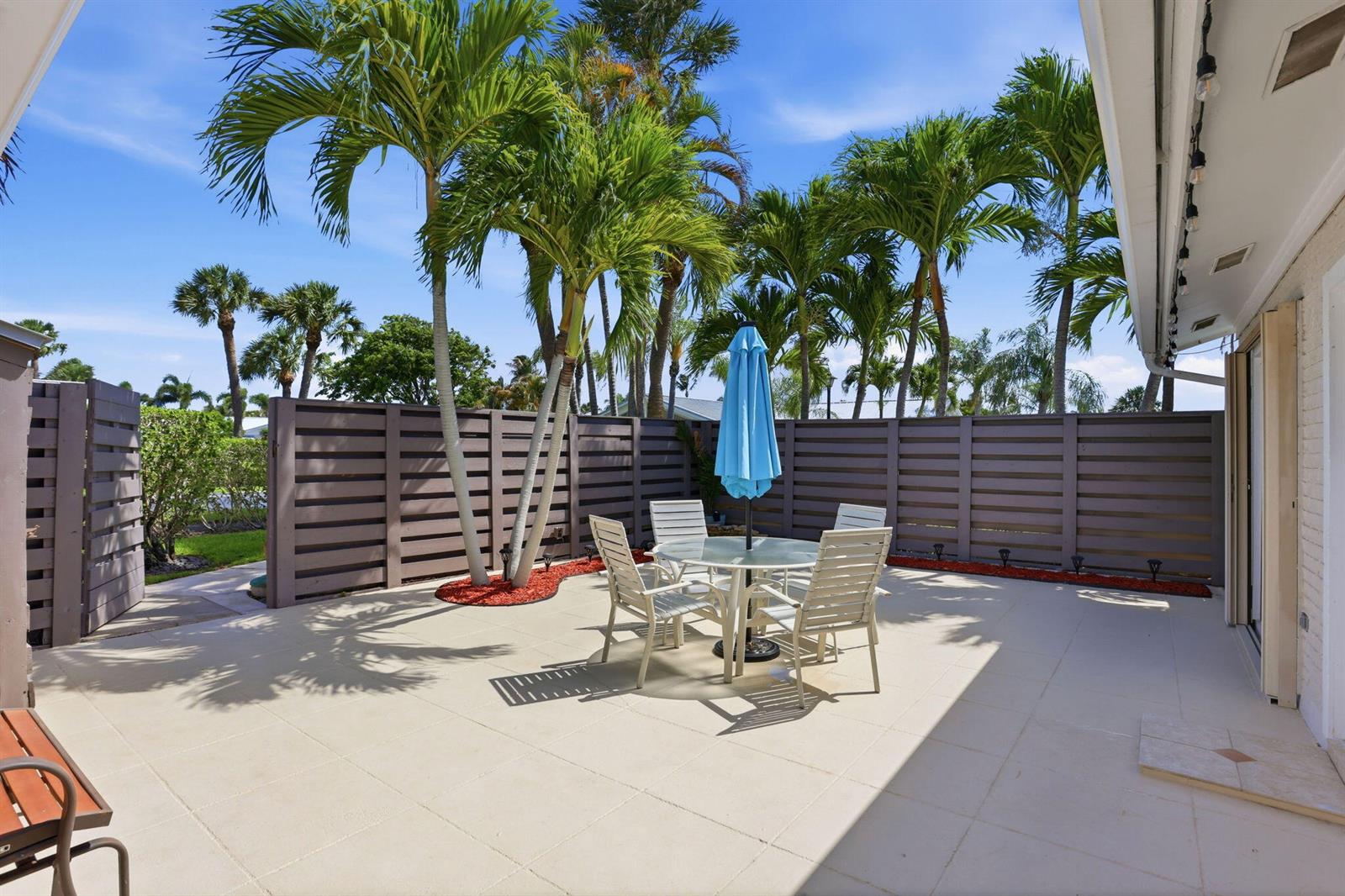A paved patio features a dining set with a blue umbrella and palm trees — 1801 S Us Hwy 1 # 3a, Jupiter FL 33477, JUPITER, FL