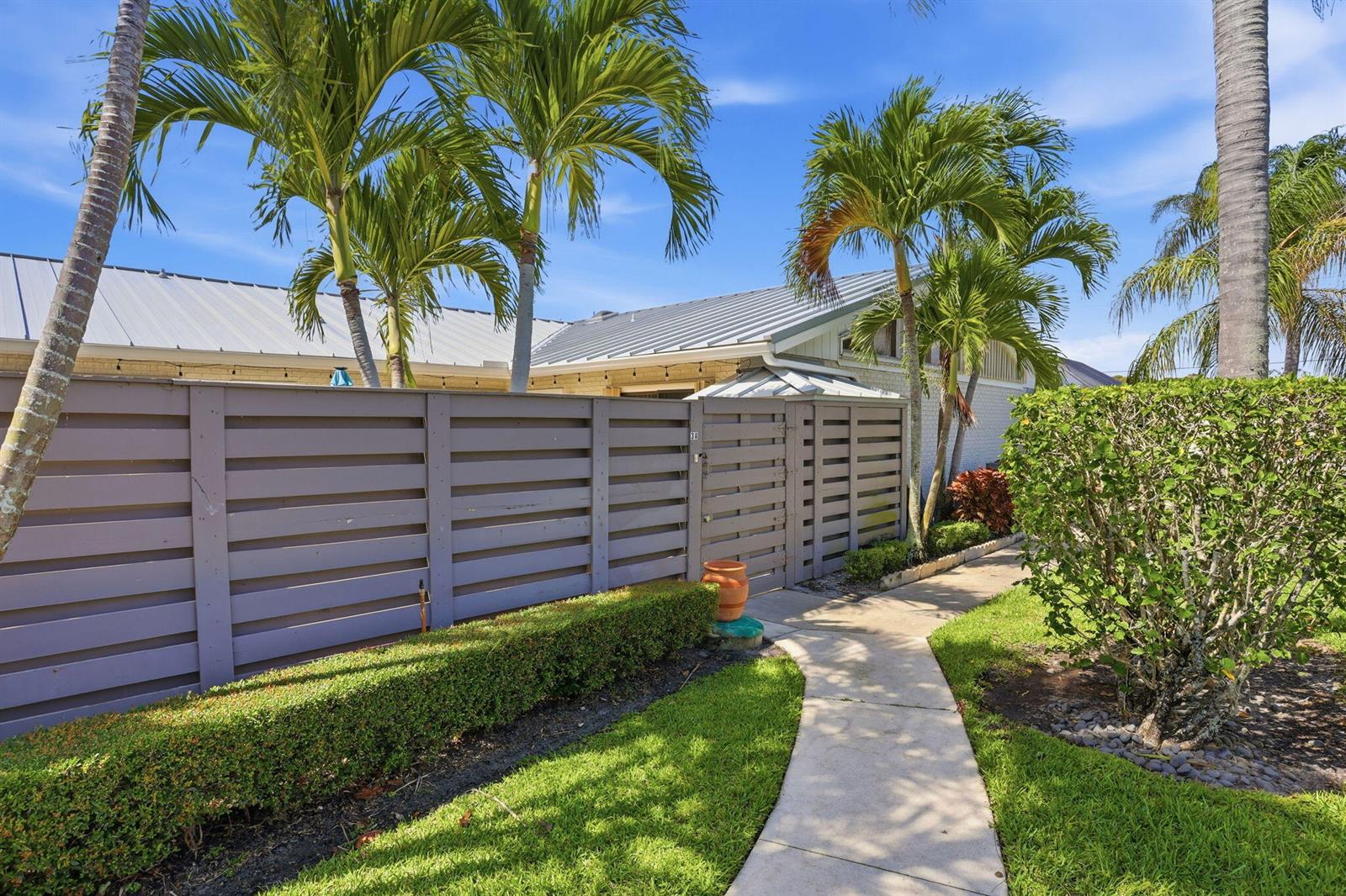 A concrete walkway leads to a wooden gate and fence in front of a house — 1801 S Us Hwy 1 # 3a, Jupiter FL 33477, JUPITER, FL