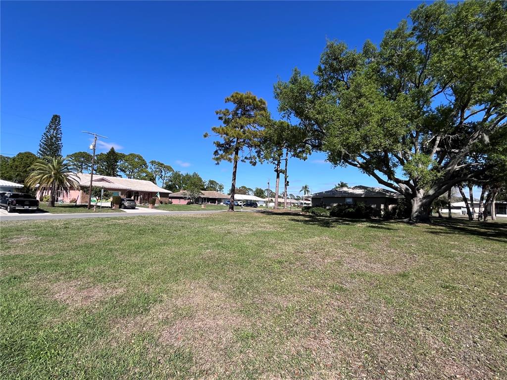 A grassy vacant lot sits in front of suburban houses under a clear blue sky — 618 RUBENS DRIVE UNIT 618, NOKOMIS, FL
