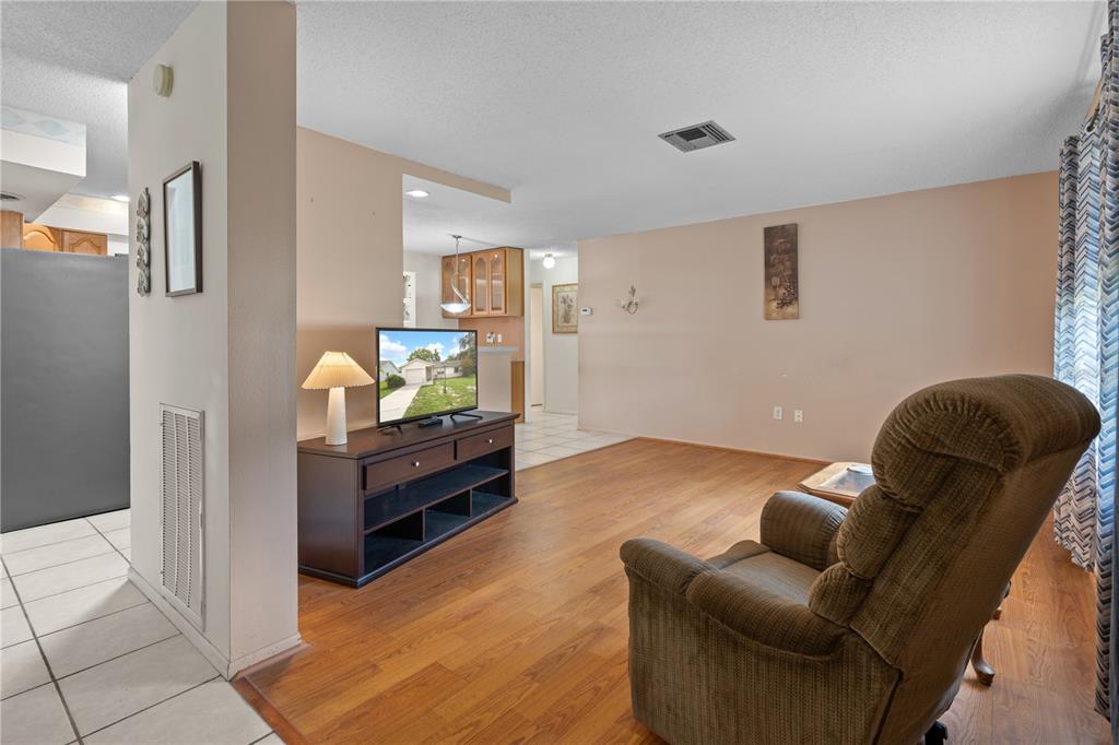A living room with wood-look flooring, a brown recliner, and a television on a stand — 2234 MARINER BOULEVARD, SPRING HILL, FL