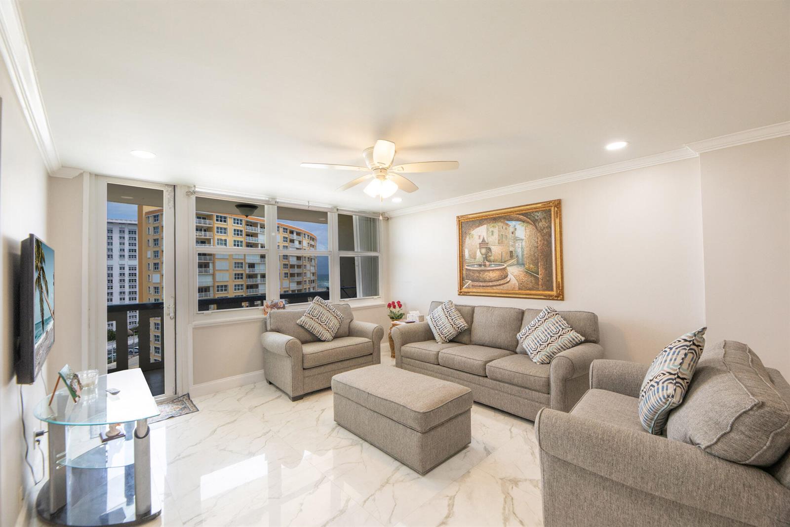 A living room features gray furniture, a marble floor, and a view of nearby buildings — 305 N Pompano Beach Boulevard # 1007, Pompano Beach FL 33062, POMPANO BEACH, FL