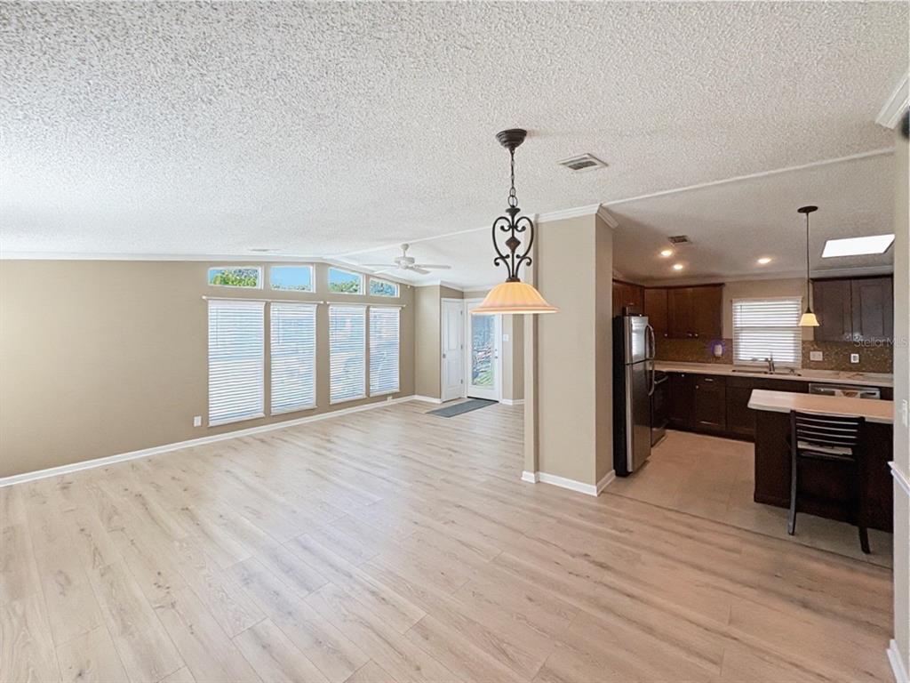 A side view of a beige manufactured home with a screened-in porch and grassy yard — 601 ROBIN LANE, WILDWOOD, FL