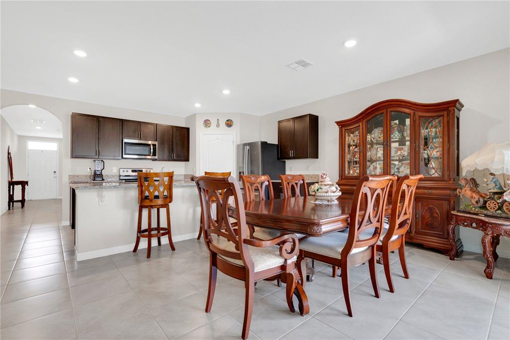 A dining area with a wooden table and chairs sits adjacent to a kitchen with cabinets — 1735 PARK SIDE AVENUE, KISSIMMEE, FL