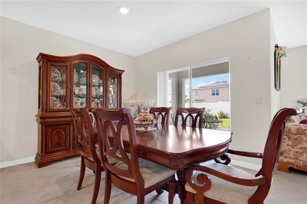 A dining room features a wooden table and hutch set, tile flooring, and a sliding door — 1735 PARK SIDE AVENUE, KISSIMMEE, FL