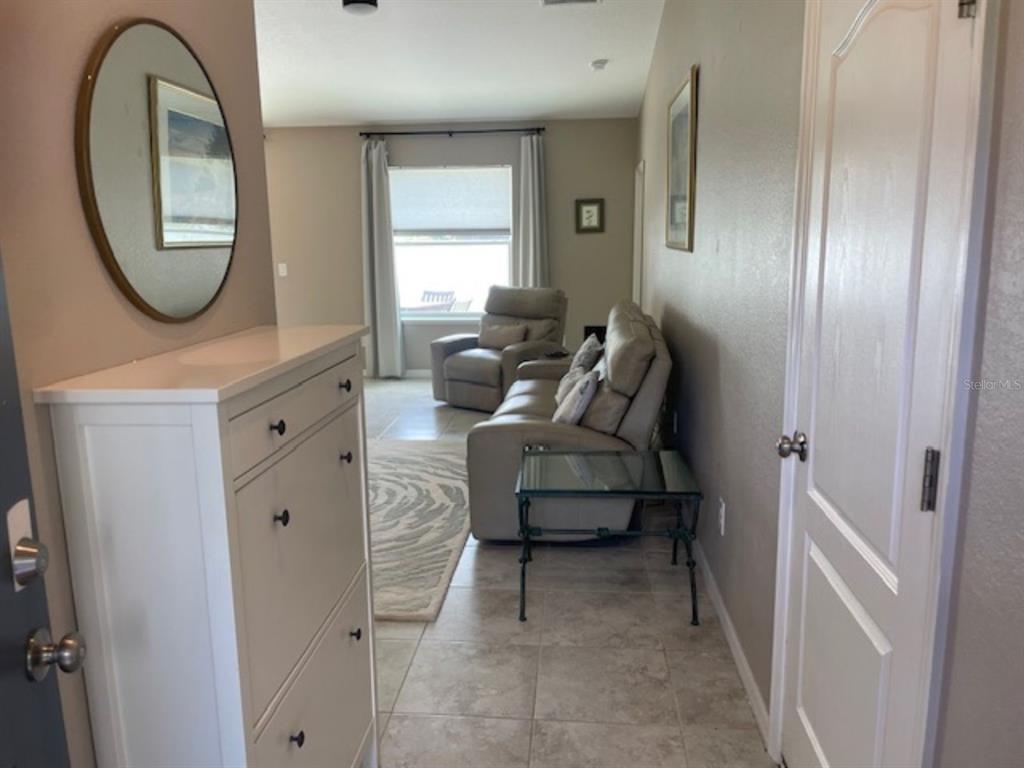 A hallway with a white cabinet and mirror leads into a living room with seating — 2966 BAY CITY TERRACE, NORTH PORT, FL