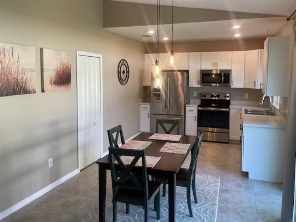 A dining area with a dark table and chairs sits adjacent to a white kitchen — 2966 BAY CITY TERRACE, NORTH PORT, FL