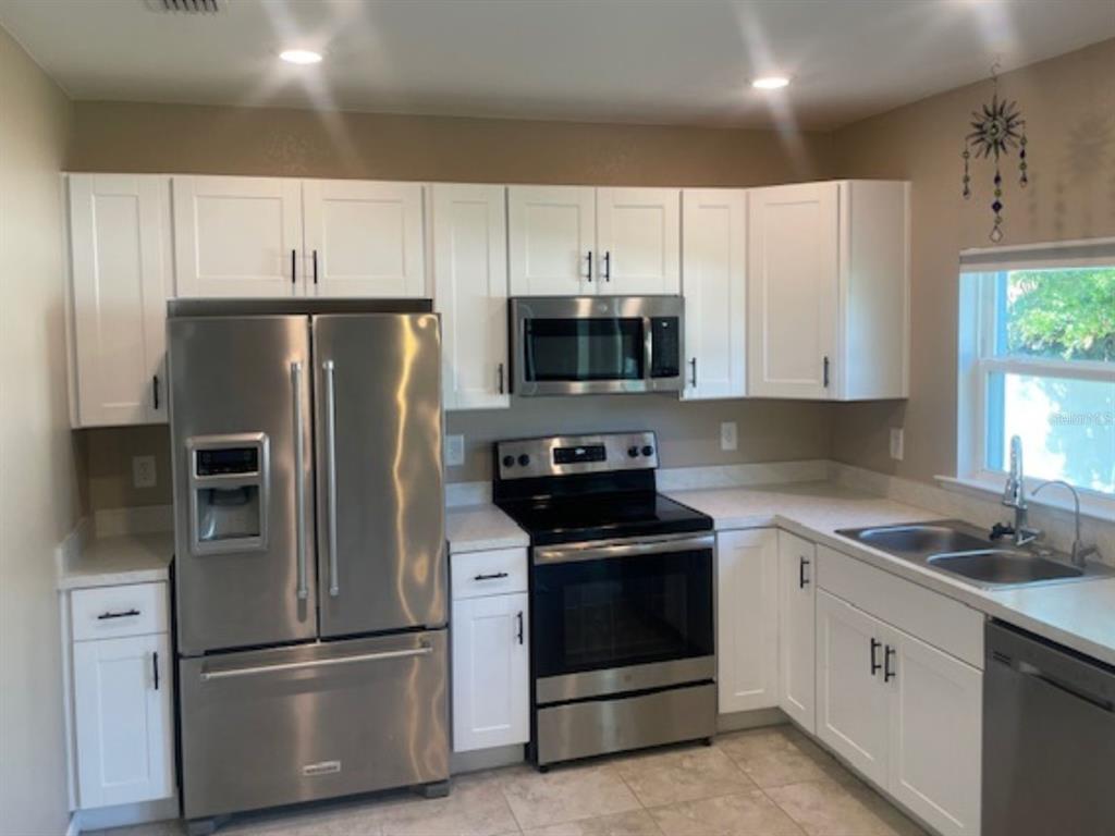 A kitchen features white cabinets, stainless steel appliances, and light-colored countertops — 2966 BAY CITY TERRACE, NORTH PORT, FL